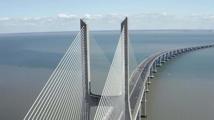 A suspension bridge carrying vehicles spans a body of water