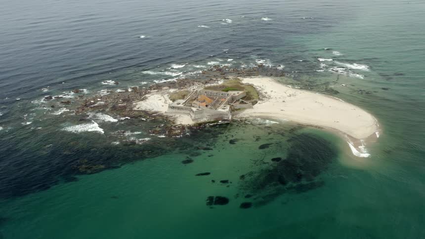 Aerial view of waves rolling over an island rocky coast
