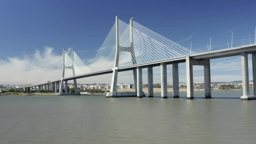 A large concrete bridge spans a river next to a city