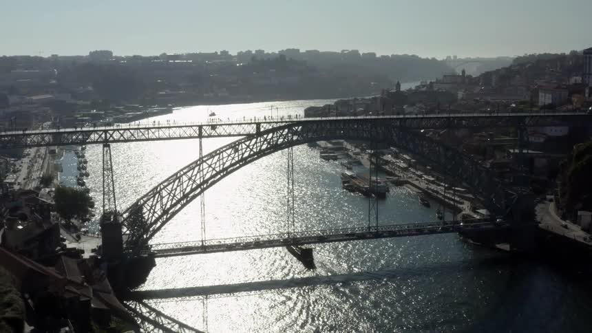 An aerial view of a ship going under a bridge