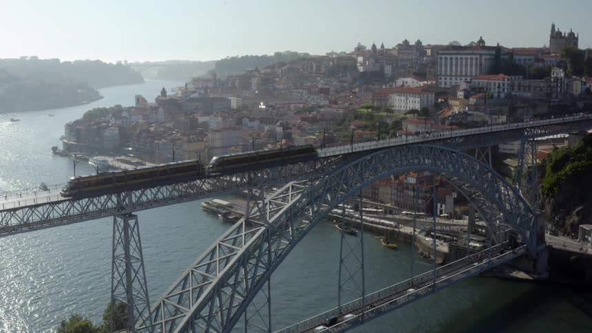 A train is traveling over a bridge to a big neighborhood