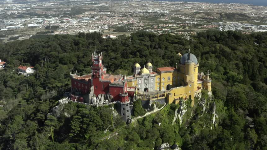 A castle on a hill with a skyline and shore in the distance