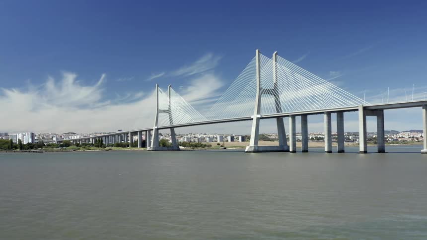 A bridge with vehicles with buildings the sky and clouds in the background
