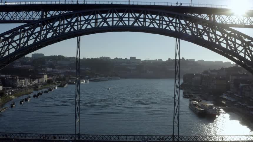 Cars and people are traveling over a bridge over a city ocean harbor
