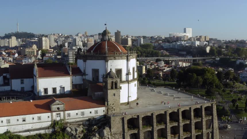 An aerial view of a city with people walking past a large building with a dome and birds flying around