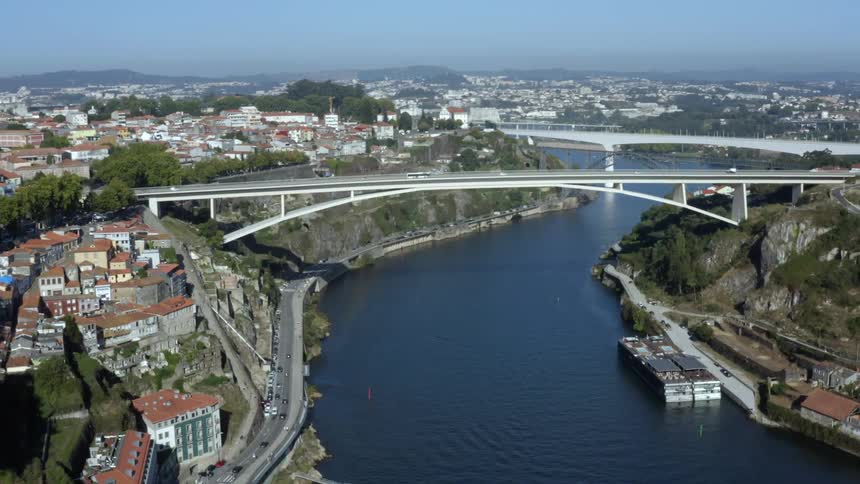 A river with bridges and vehicles with buildings the sky and clouds in the background