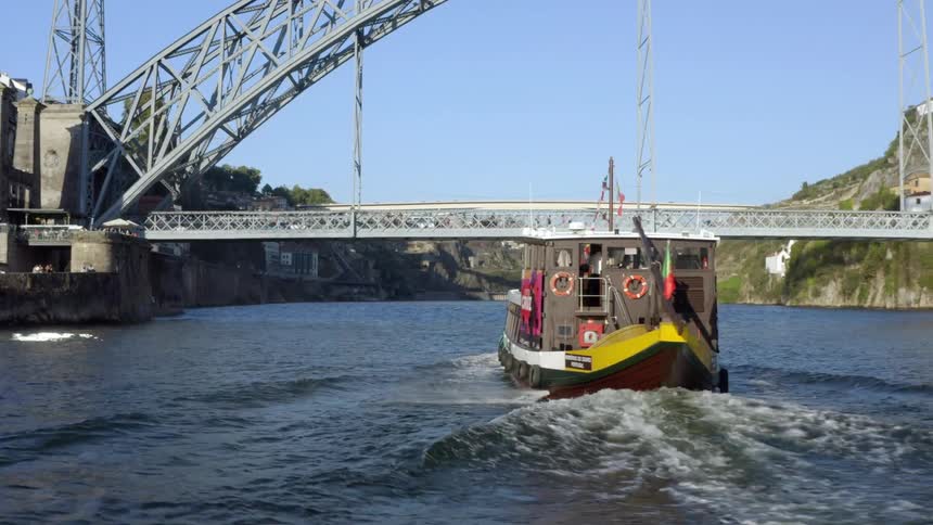 A boat travels along a waterway beneath a bridge on a sunny day