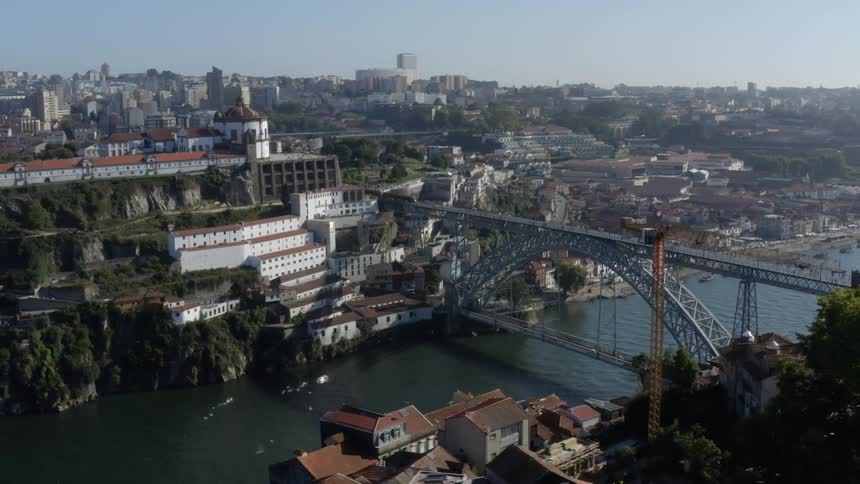 A train is traveling on a bridge over a river to a big city