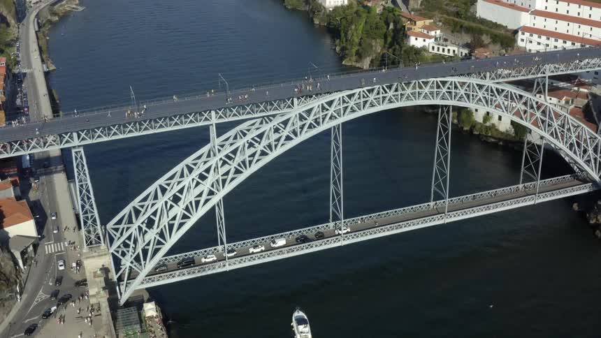 Traffic crosses bridge spanning river while pedestrians cross on higher level of bridge and bridge passes underneath