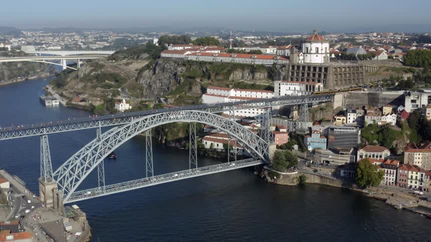 Aerial view of tram and people going over arch bridges over river