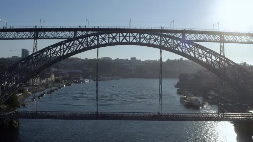 People walk on a pedestrian bridge that sits above a vehicle bridge over a river