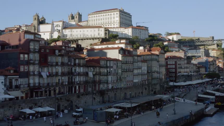 Aerial view of people walking along promenade next to river and city buildings
