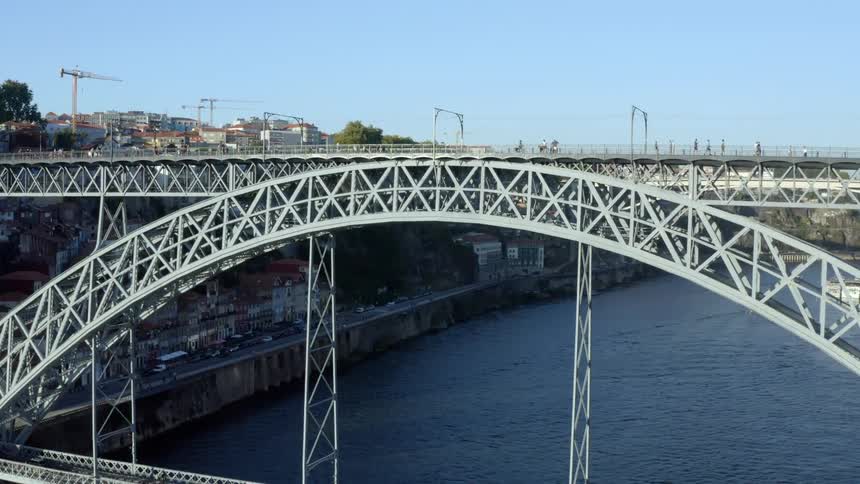 A walking bridge spanning a river in a city during the day