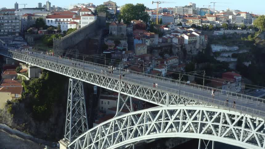 Aerial view of people going over arch bridge with city buildings on background