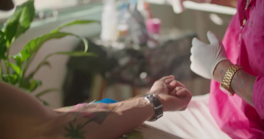 A tattoo artist talks to his client after tattoo the inside of his forearm