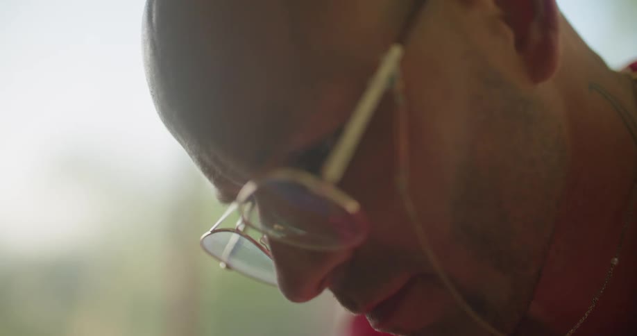 A man wearing glasses leans down to look at something