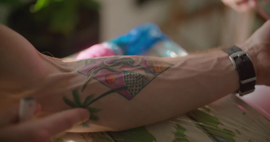 A man shows another person parts of his tattoo on his arm