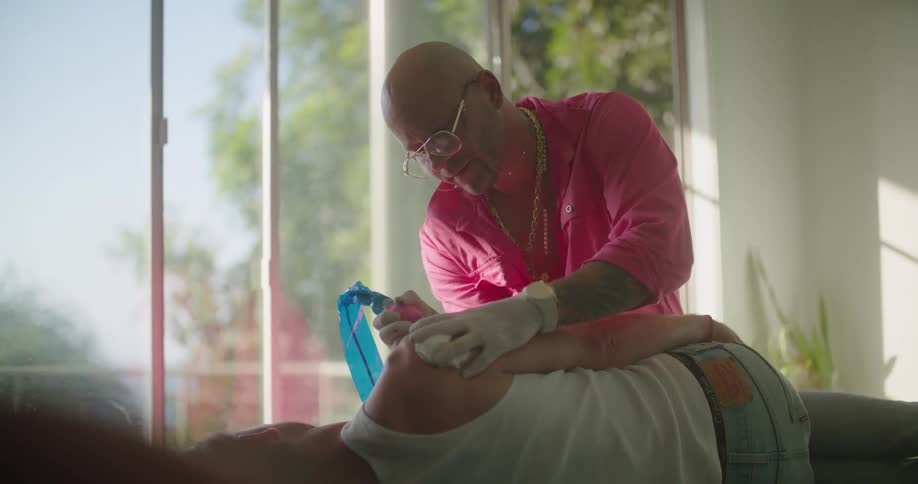 A tattoo artist tattoos a persons arm