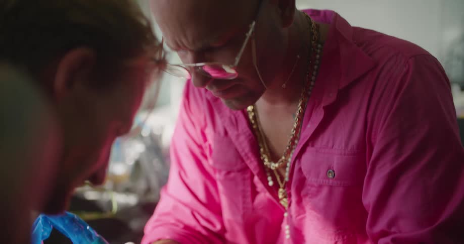 A tattoo artist works on a design on a mans forearm