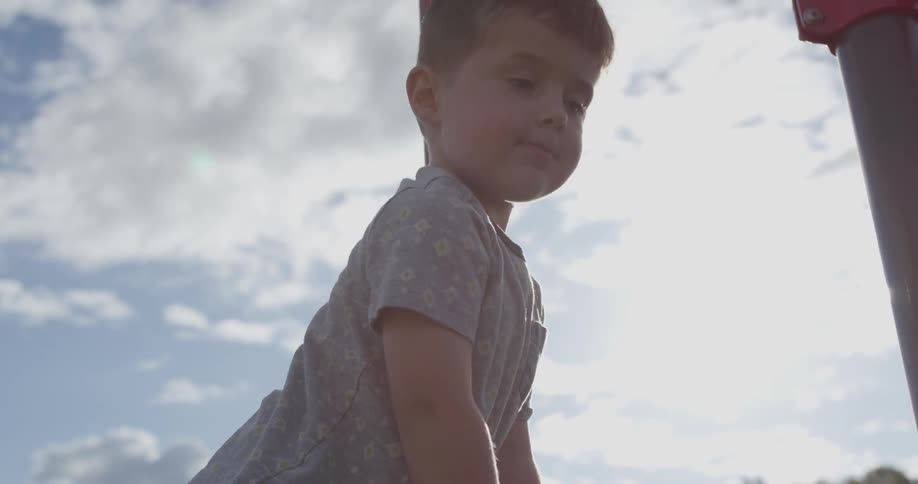 A boy is climbing up a jungle gym
