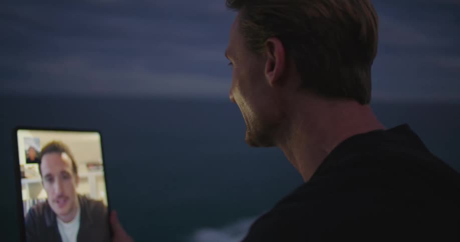 A man holds a tablet as he talks to another man on video call
