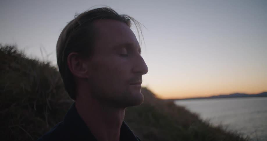 A man closes his eyes while staring out across the ocean