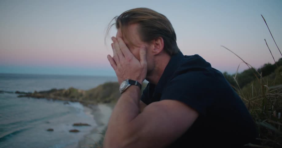 A man sitting by a body of water