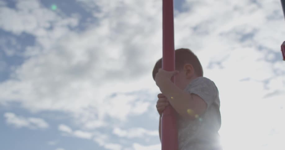 A boy is holding onto a metal pole in the air