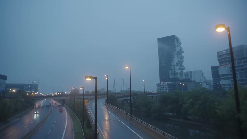 Cars drive on city highways on a cloudy day at dusk