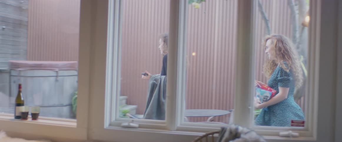 Two women walk out of the house to sit by the fire