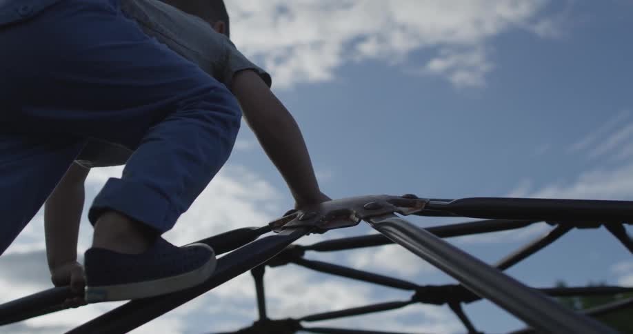 A boy reaches the top of a jungle gym