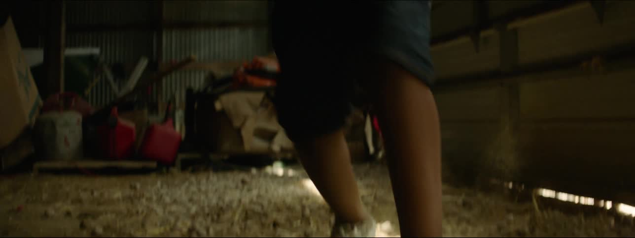A young boy is smiling while dancing and spinning around on sawdust in a garage