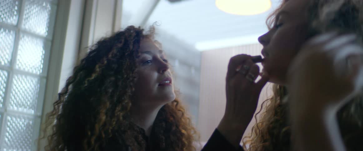 Two women putting on makeup in a room