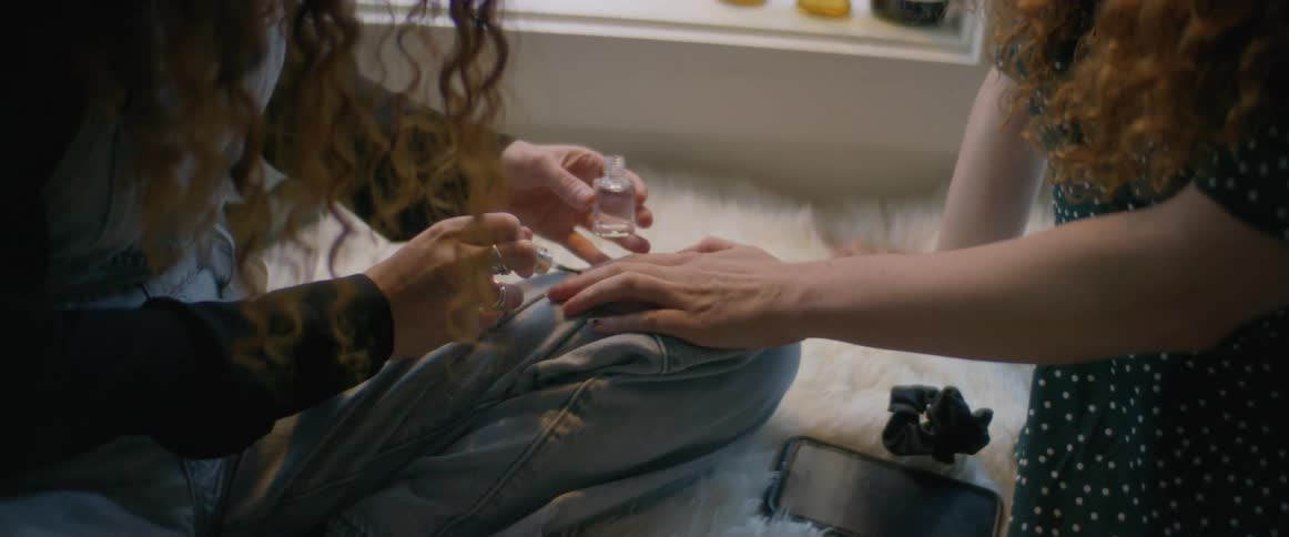A woman is painting another womans finger nails
