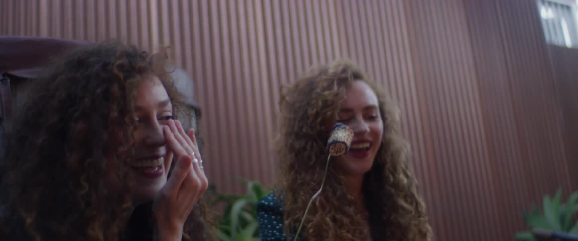 Two women are having fun roasting marshmallows on a residential patio during the day