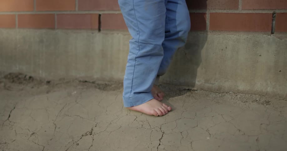 A person is walking barefoot on a sidewalk
