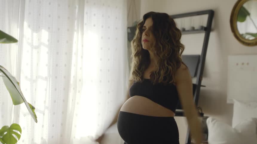 A pregnant woman exercises in the living room of a house during the day