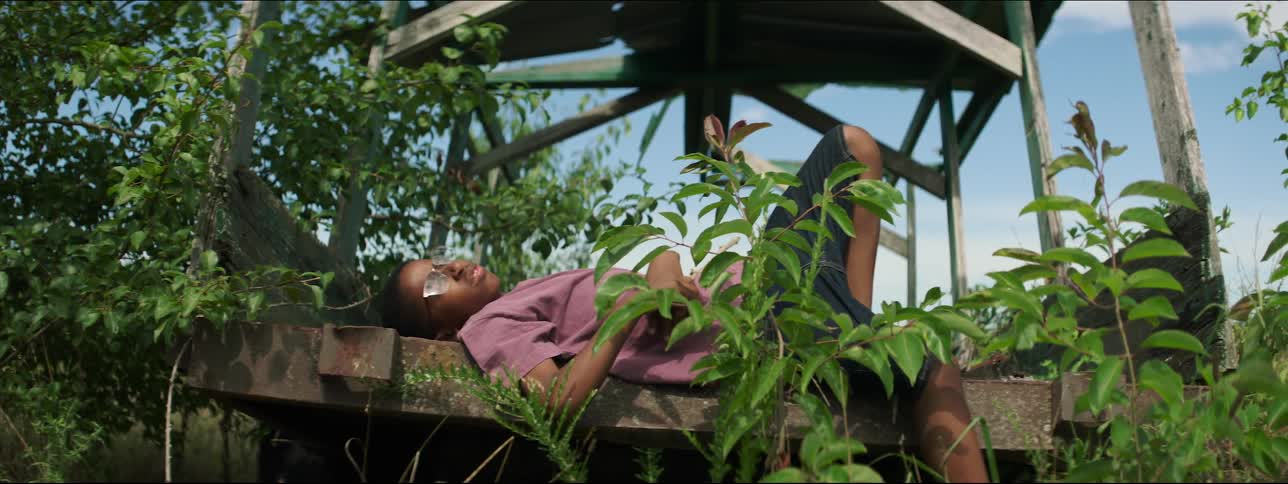 Boy reclines on platform under structure holding stick