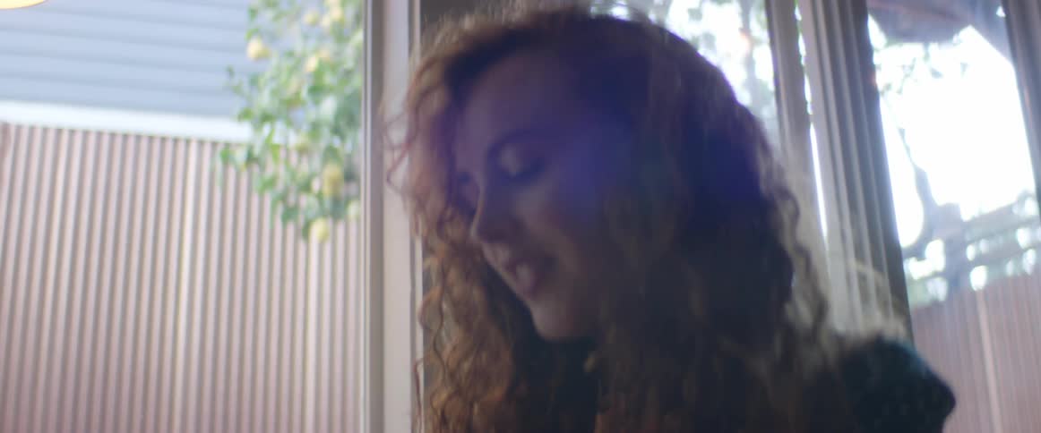 A woman with long brown hair is looking ahead and smiling