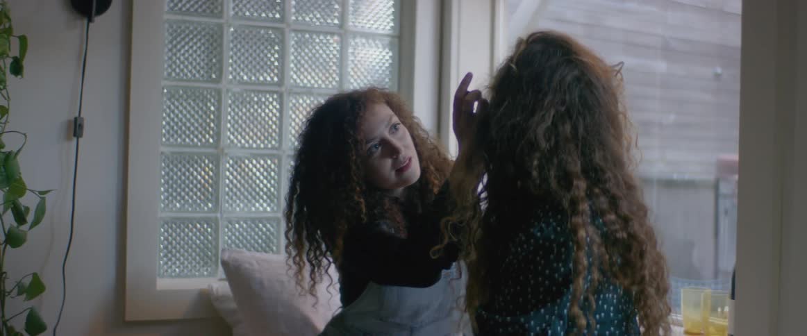 Two women putting on makeup in a room together