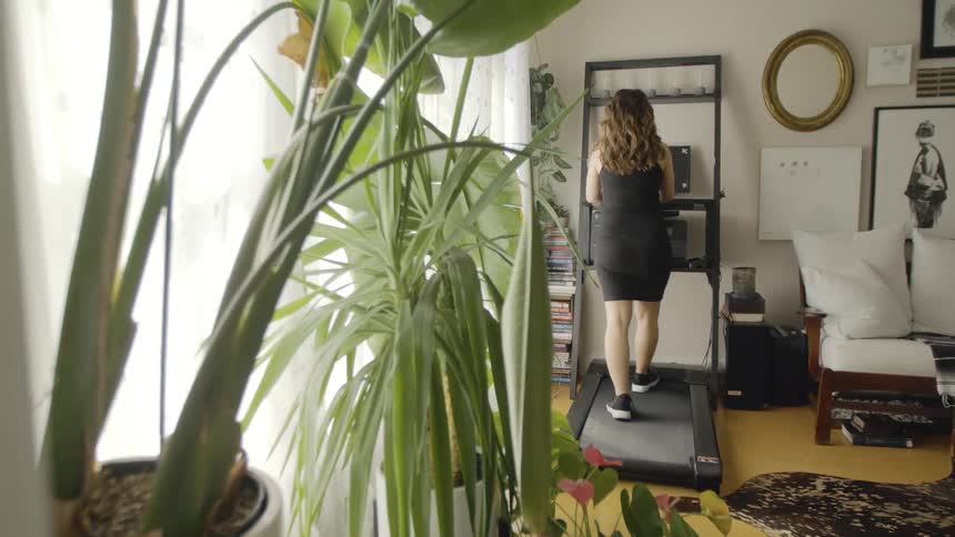 A woman walks on a treadmill at home during the day