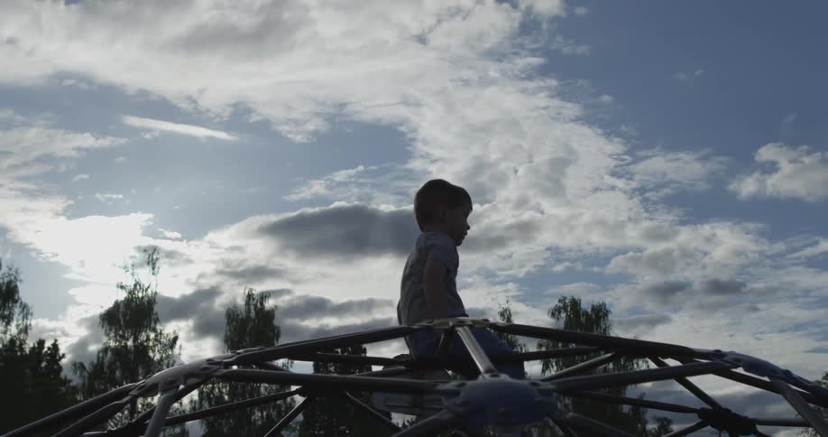 A boy sits on a jungle gym