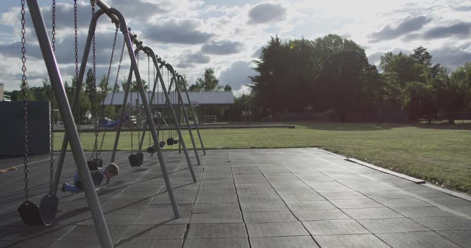 A child plays alone on a swing set