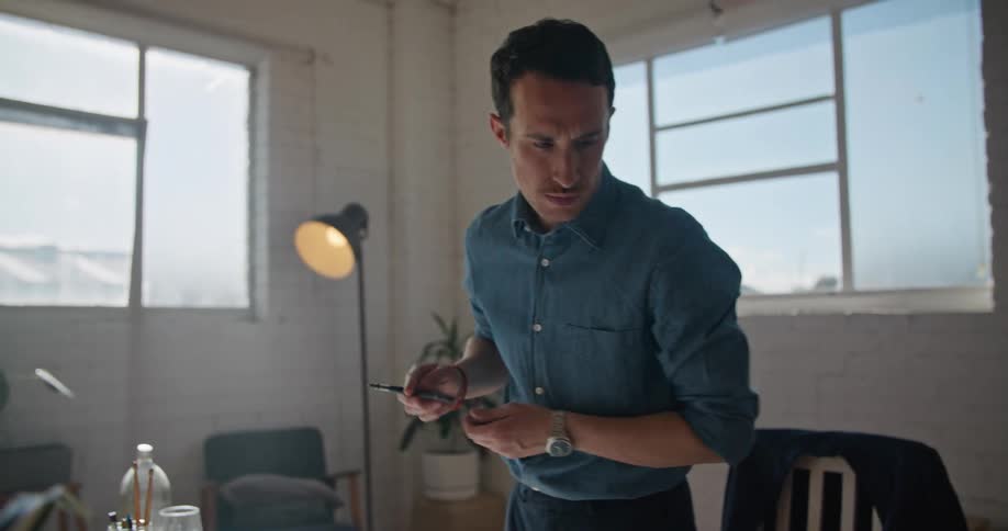 Man writes on paper on table top after typing on laptop