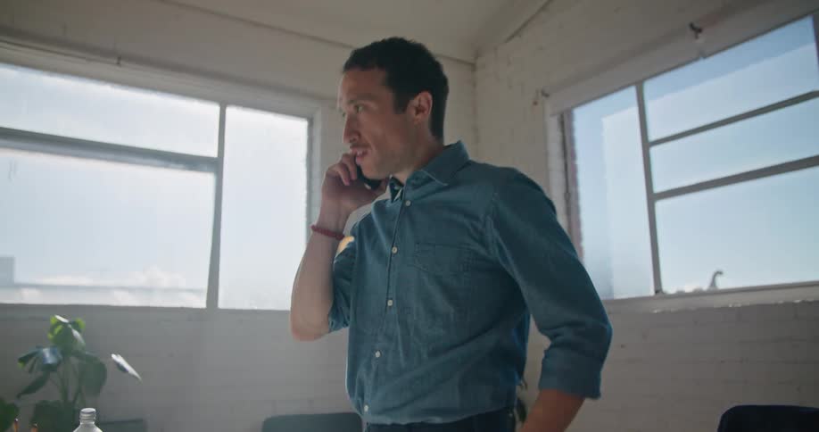 A man talks on his smartphone while standing in an office during the day