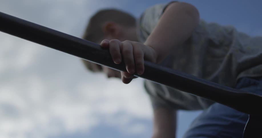 A boy is climbing on top of a jungle gym