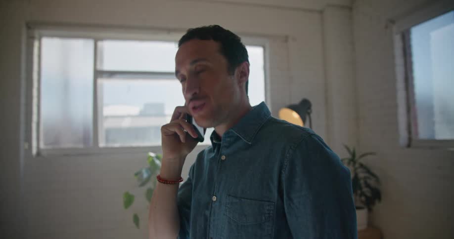 A man talks on his smartphone while looking over blueprints on a table