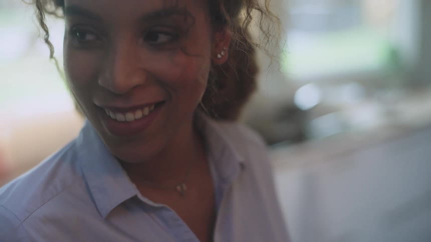 A woman smiles while standing in her kitchen