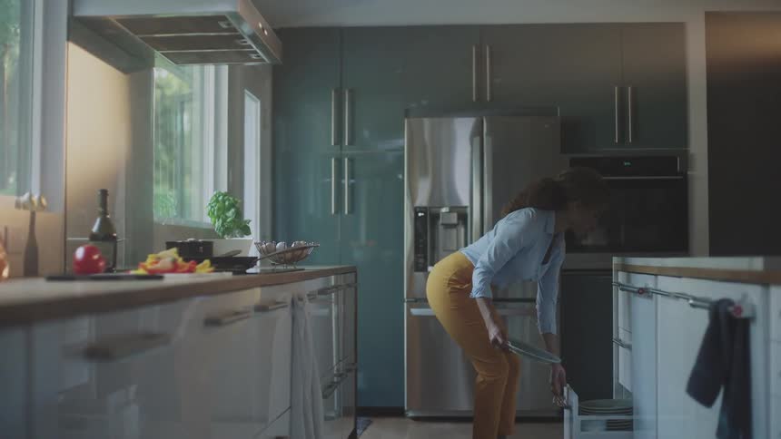 A woman takes a dish from the drawer as she cooks