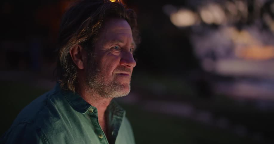 Mature man sitting outdoors at night typing on a laptop